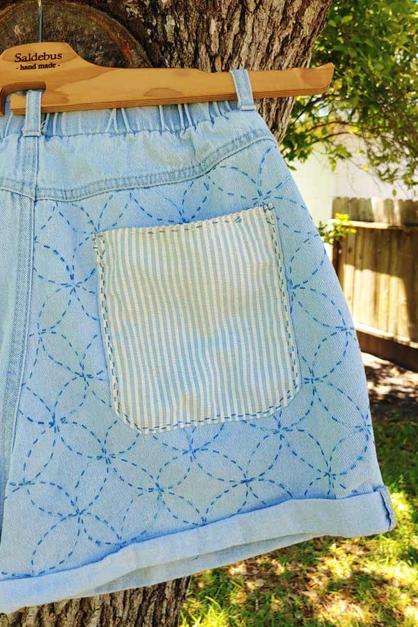 blue jean shorts with a hand-stitched pocket patch 