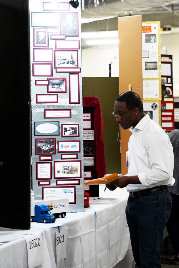 a man holding a clip board looking at a trifold history project