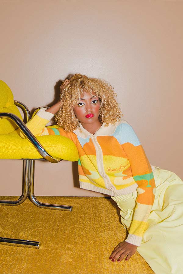 a woman wearing shades of yellow leaning on a yellow chair