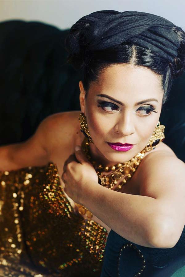 musician Azul Barrientos posing with a gold sequined dress and purple lip stick