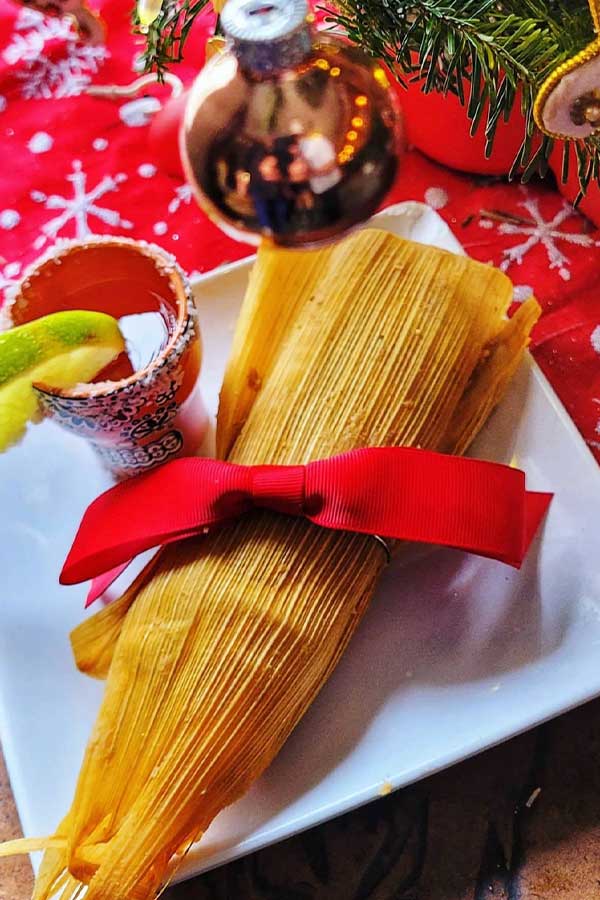 a tamale with a red ribbon around it on a white plate
