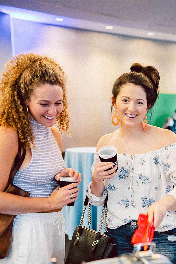 two women holding drinks and smiling in the Bullock Museum