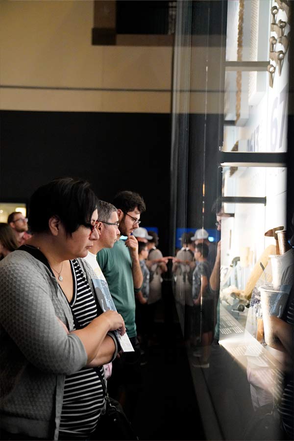 group of adults looking at a large display case full of artifacts from La Belle in the Bullock Museum