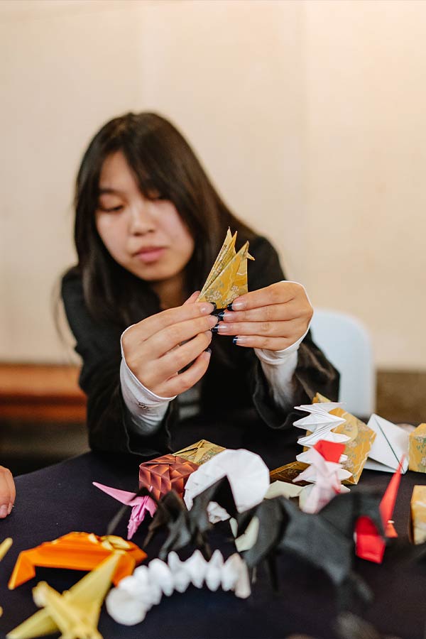 a woman making origami out of a decorative yellow piece of paper