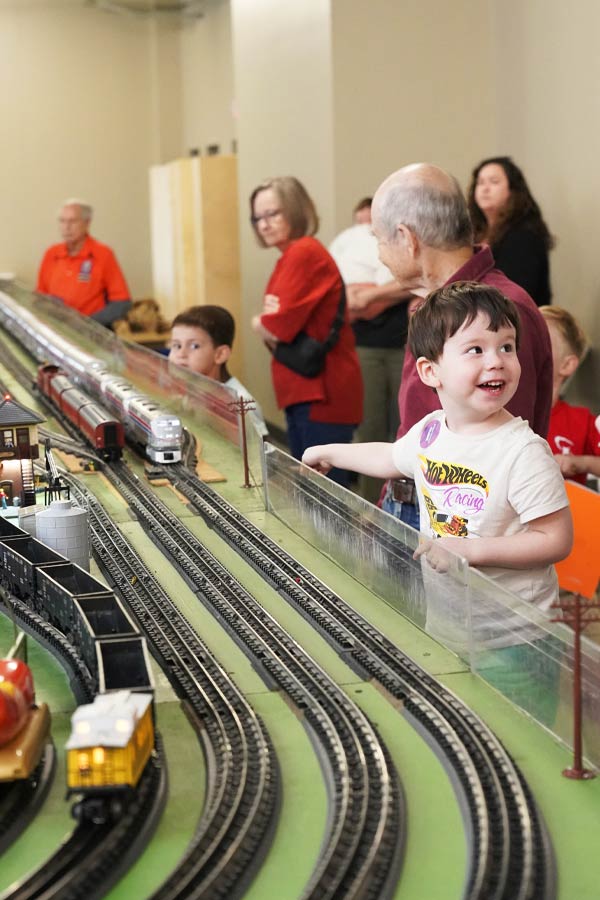 a child pointing at a set of model trains on tracks.