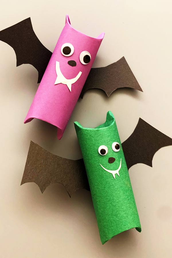 Two handmade craft bats made out of toilet paper rolls, one is pink and one is green