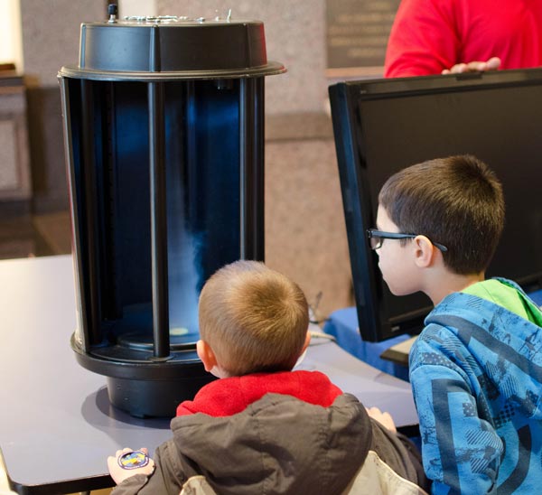 Children watching a vortex machine create a tornado
