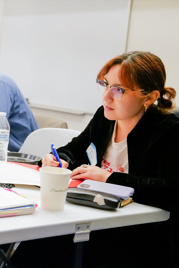 a woman wearing glasses writing something down in the Bullock Museum classrooms