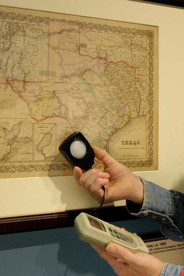a hand holding a light meter up to a framed map