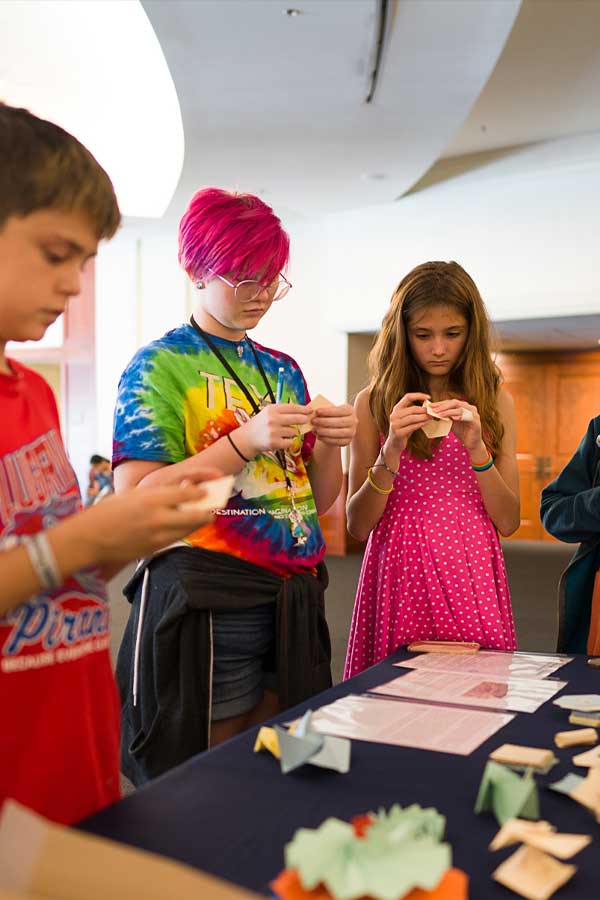 Three teens standing together working on a craft at the Bullock Museum