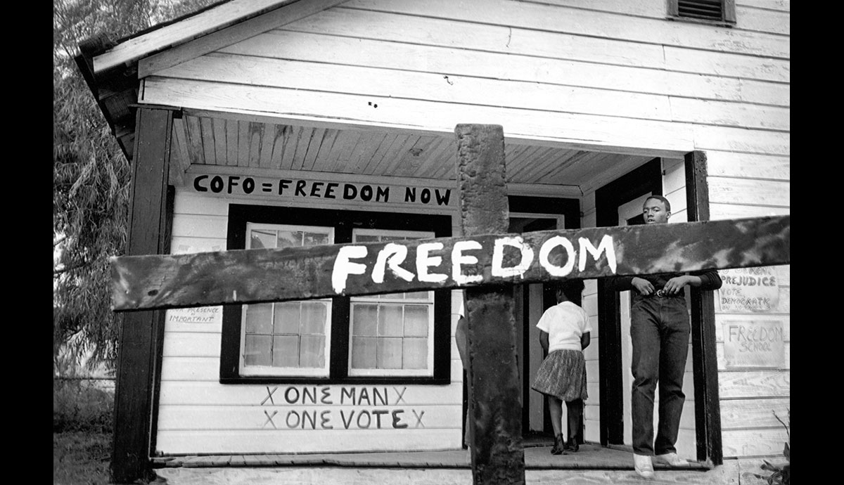 A civil rights worker transformed this burned cross with a painted message.  © 1964 Tamio Wakayama, Courtesy CDEA.