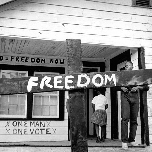 After the Ku Klux Klan burned this cross in front of a Mississippi Delta Freedom House, a civil rights worker transformed it with a painted message. Indianola, Mississippi. ©1964 Tamio Wakayama, Courtesy CDEA