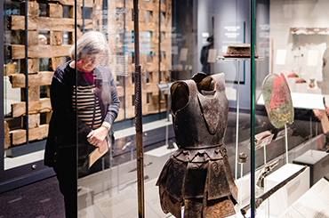 A woman looks at a case in the galleries containing an armor plate.