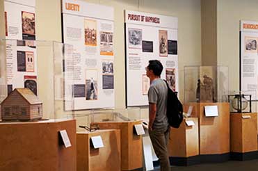 man looking at wall graphics and artifacts in cases in the Black Citizenship in the Age of Jim Crow exhibit at the Bullock Museum