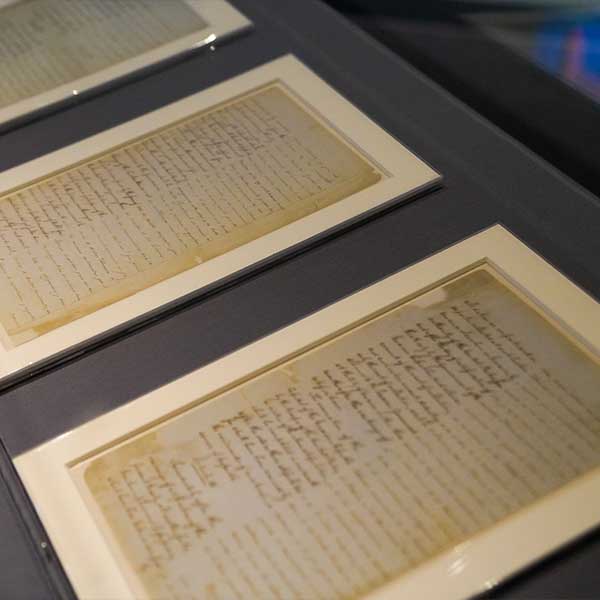 three aged documents in a display case