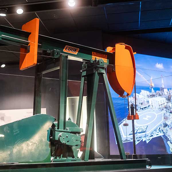 a green and orange pumpjack on display in the Texas Oil and Gas exhibit in the Bullock Museum