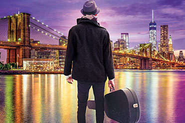 Man with a guitar case looks out at the skyline