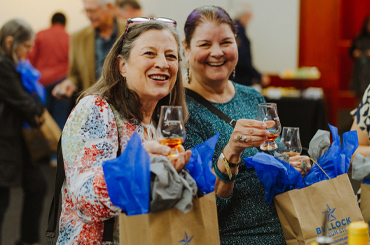 two women holding Bullock Museum goodie bags and smiling.