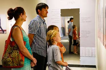 a family looking at photographs in an exhibition at the Bullock Museum