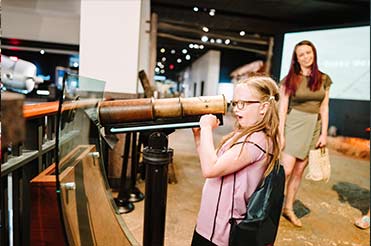 a young girl looking through a spyglass in the Bullock Museum