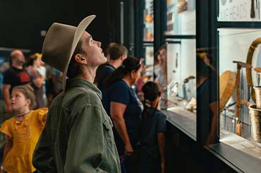 young boy wearing a cowboy hat looking up at a large display case in the Bullock Museum