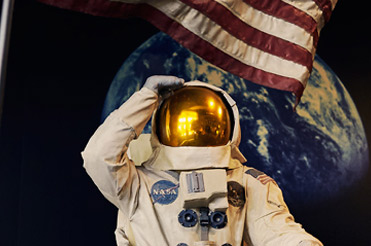 Statue of astronaut on the moon saluting with an American flag in the background