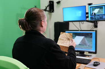 An educator instructing a virtual class in front of a green screen.