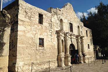 exterior of the facade Alamo building, a tan stone building with columns
