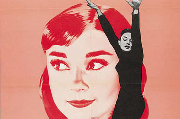 Audrey Hepburn posing in front of a poster of her face