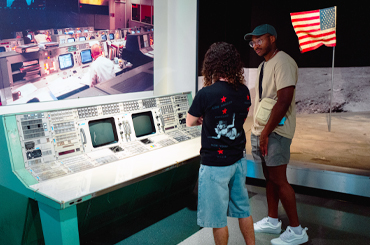 Two people looking at a NASA Mission Control display at the Bullock Museum.