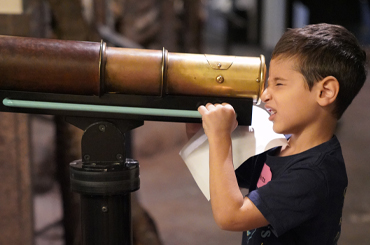 a young boy looking through a telescope at the Bullock Museum