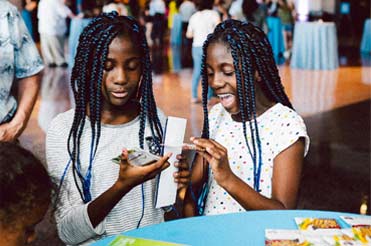 Two girls creating a craft on the first floor of the Bullock Museum