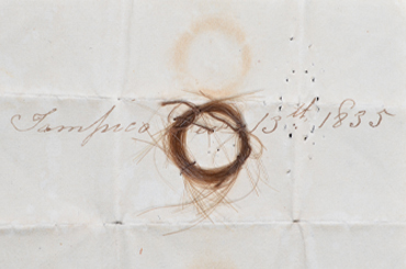 a lock of hair pinned to an aged piece of paper that says, "Tampico 1835"