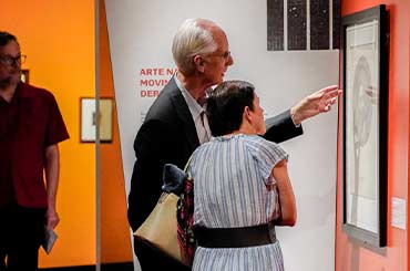 two adults looking at artwork in the Kelley Art Collection exhibit in the Bullock Museum