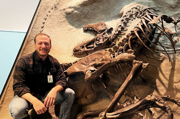A man posing next to dinosaur fossils.