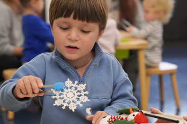A young child doing a snowflake craft activity.