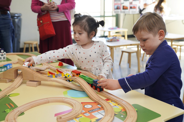 two children playing with a toy train set.