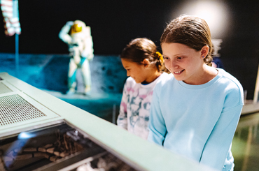 Adolescents looking at a space exhibit at the Bullock Museum.