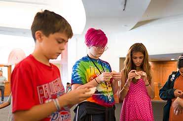 three adolescents standing working on a craft at the Bullock Museum