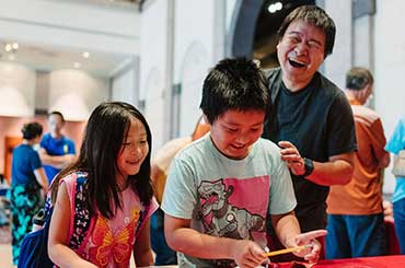 two kids and an adult laughing while doing a craft in the Bullock Museum