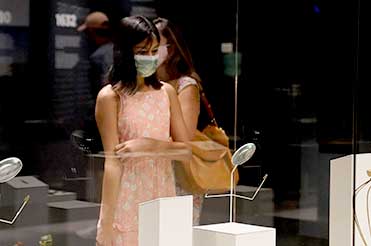 woman standing in front of a display case wearing a mask