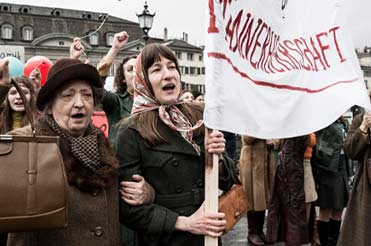 Group of women marching holding a white cloth banner