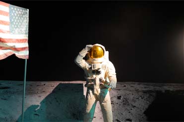 Statue of astronaut on the moon saluting standing next to an American flag in the Bullock Museum