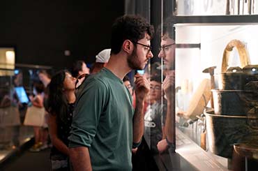 adults looking at a large display case of items recovered from the ship La Belle in the Bullock Museum