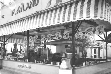 Black and white photo of booth at amusement park, sign reads, "Playland"