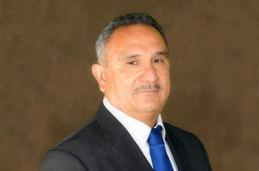 Man posed for portrait wearing blue suit and tie looking at us
