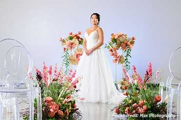 a bride in a white wedding dress surrounded by pink and green flowers in the Bullock Museum Austin Room