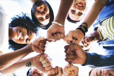 underneath shot of a diverse group of men and women with their fists together forming a circle