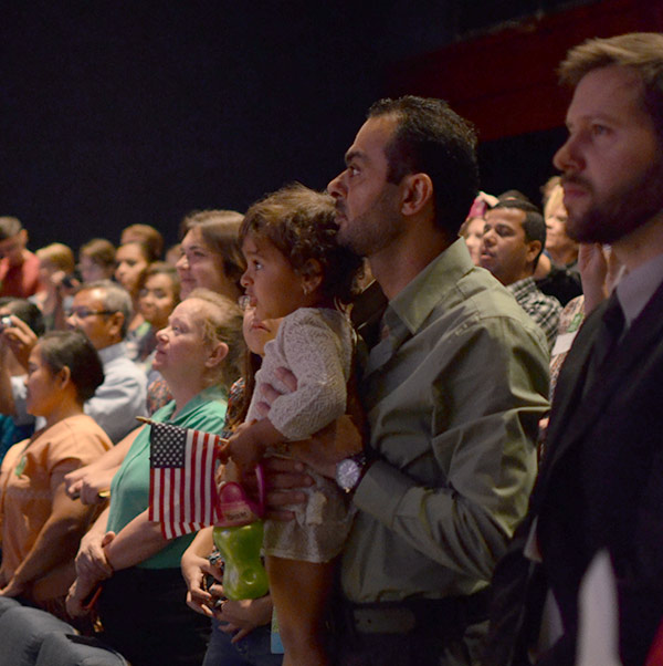 A young girl with her father at the naturalization ceremony on World Refugee Day at the Bullock Museum.