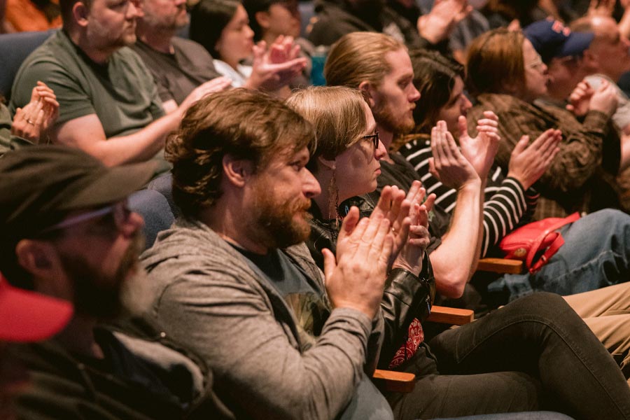 people seated in a theater clapping